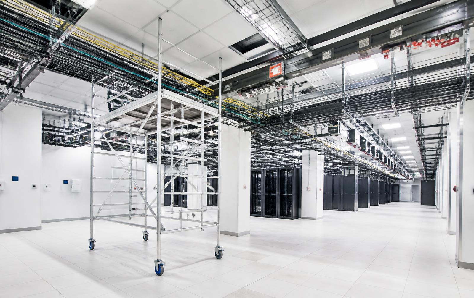 Aluminum rolling scaffold tower positioned for overhead cable tray work inside a bright data center under construction